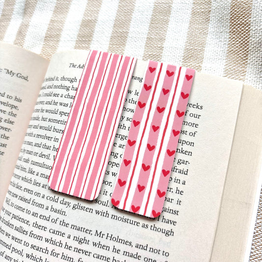 Pink striped bookmarks with red hearts on a book page.