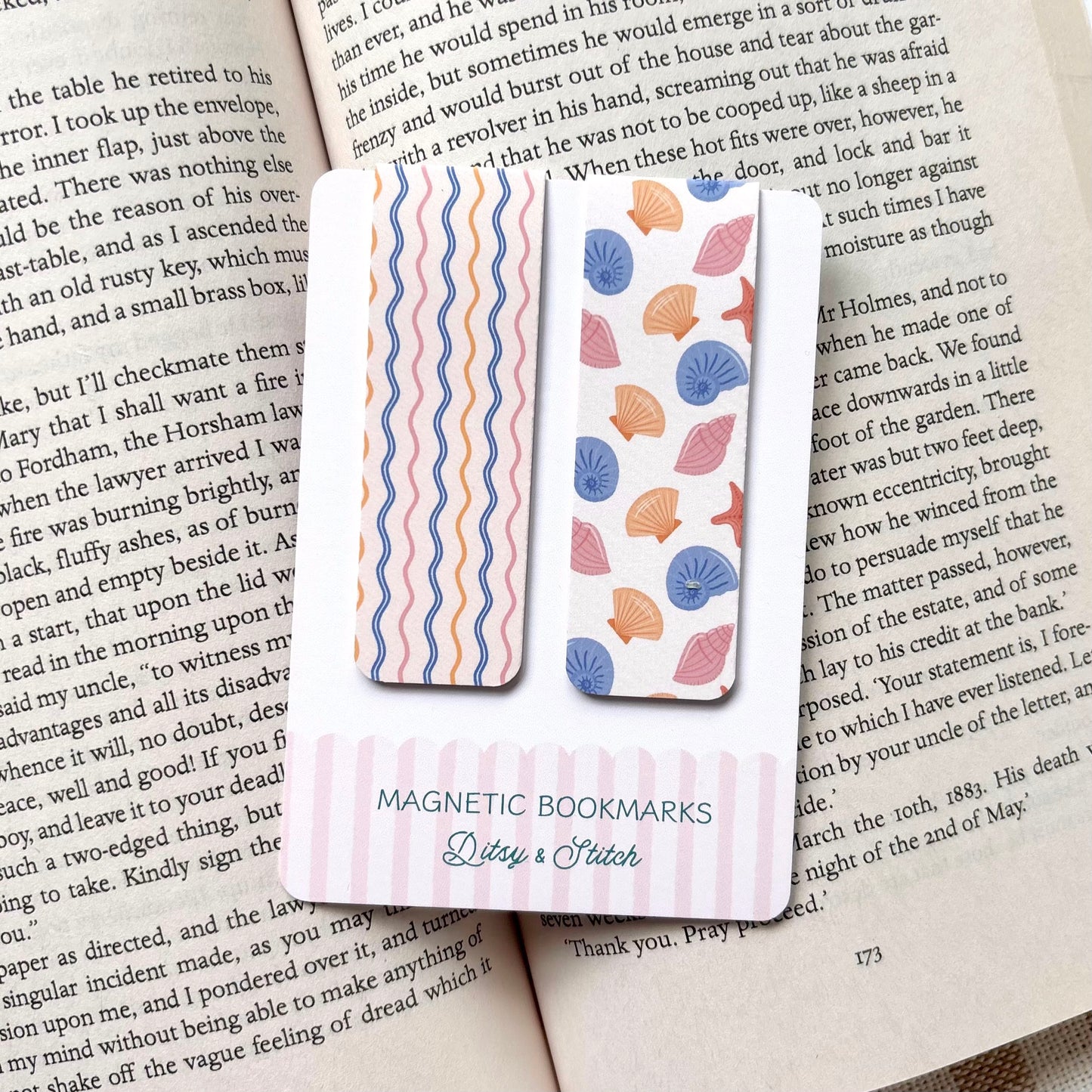 Two magnetic bookmarks with shell and wavy stripe patterns on a book page, brand 'Ditsy & Stitch' visible