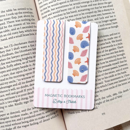 Two magnetic bookmarks with shell and wavy stripe patterns on a book page, brand 'Ditsy & Stitch' visible