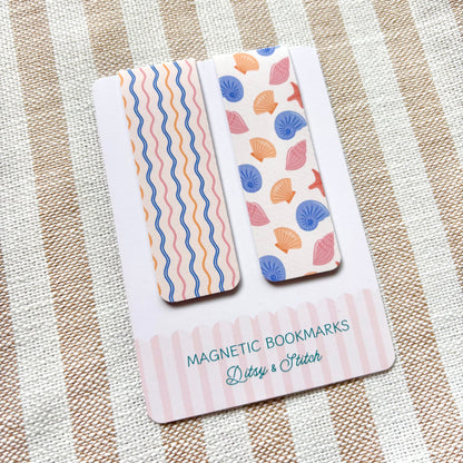 Two magnetic bookmarks with shell and wave patterns on a striped fabric background