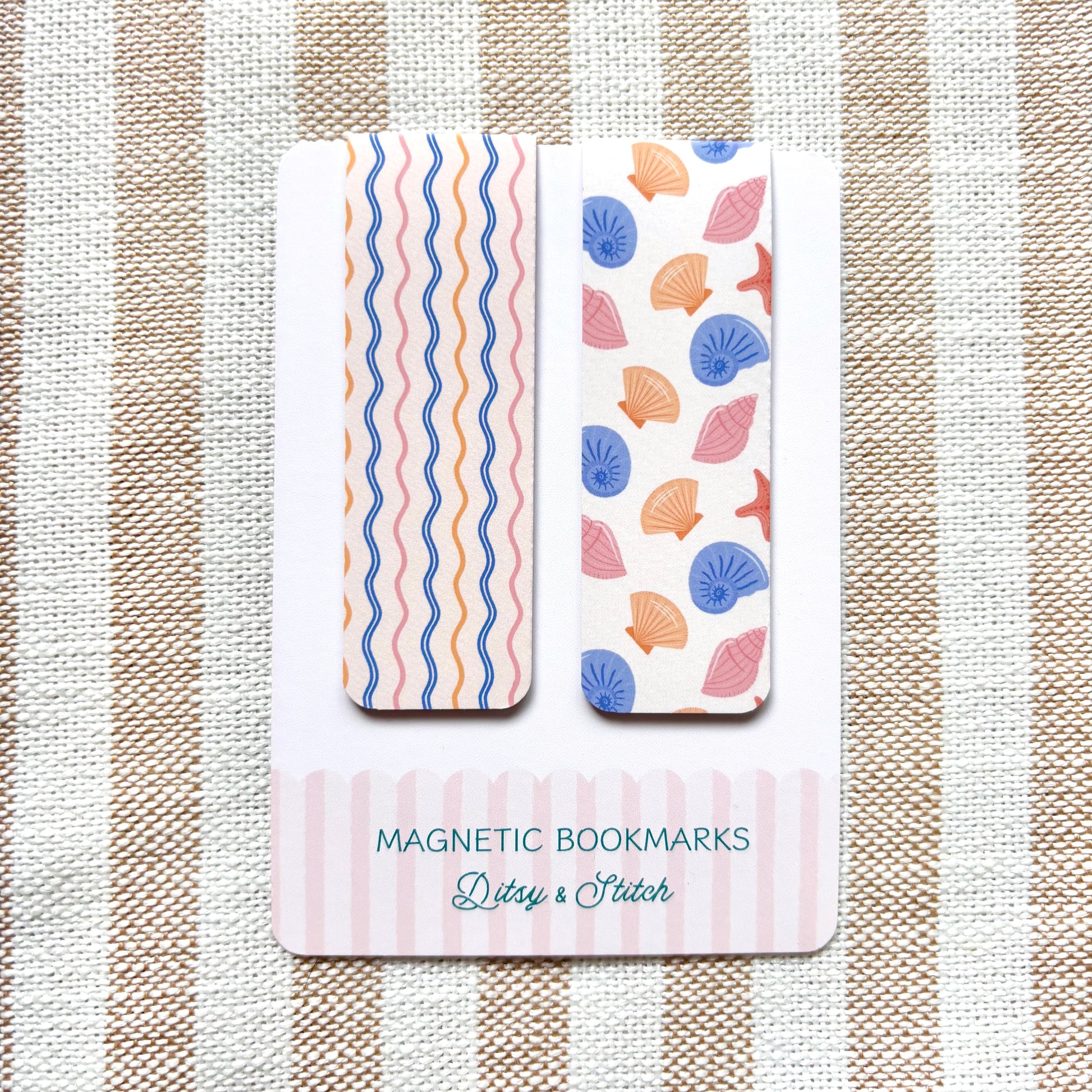 Two magnetic bookmarks with shell and wavy pattern designs on a striped fabric background.