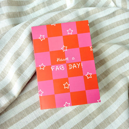 Checkered pink and orange greeting card with 'Have a FAB DAY!' text and white stars on a striped fabric background