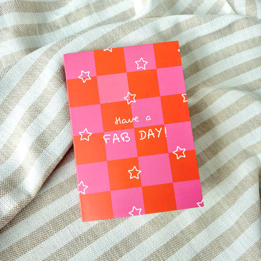 Checkered pink and orange greeting card with 'Have a FAB DAY!' text and white stars on a striped fabric background