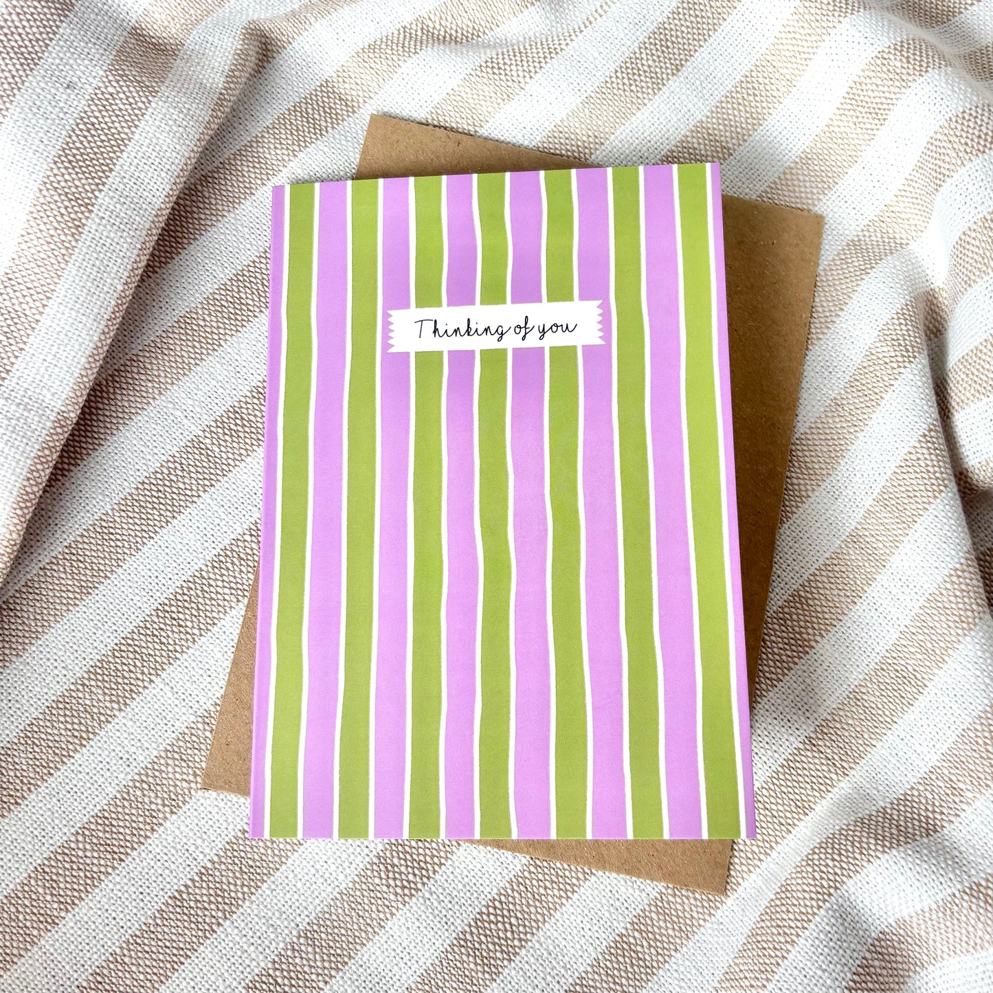 Striped card with 'Thinking of you' message on a striped fabric background