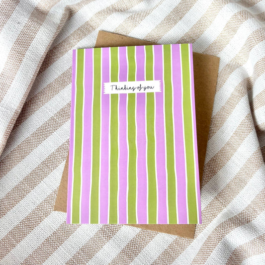 Striped card with 'Thinking of you' message on a striped fabric background