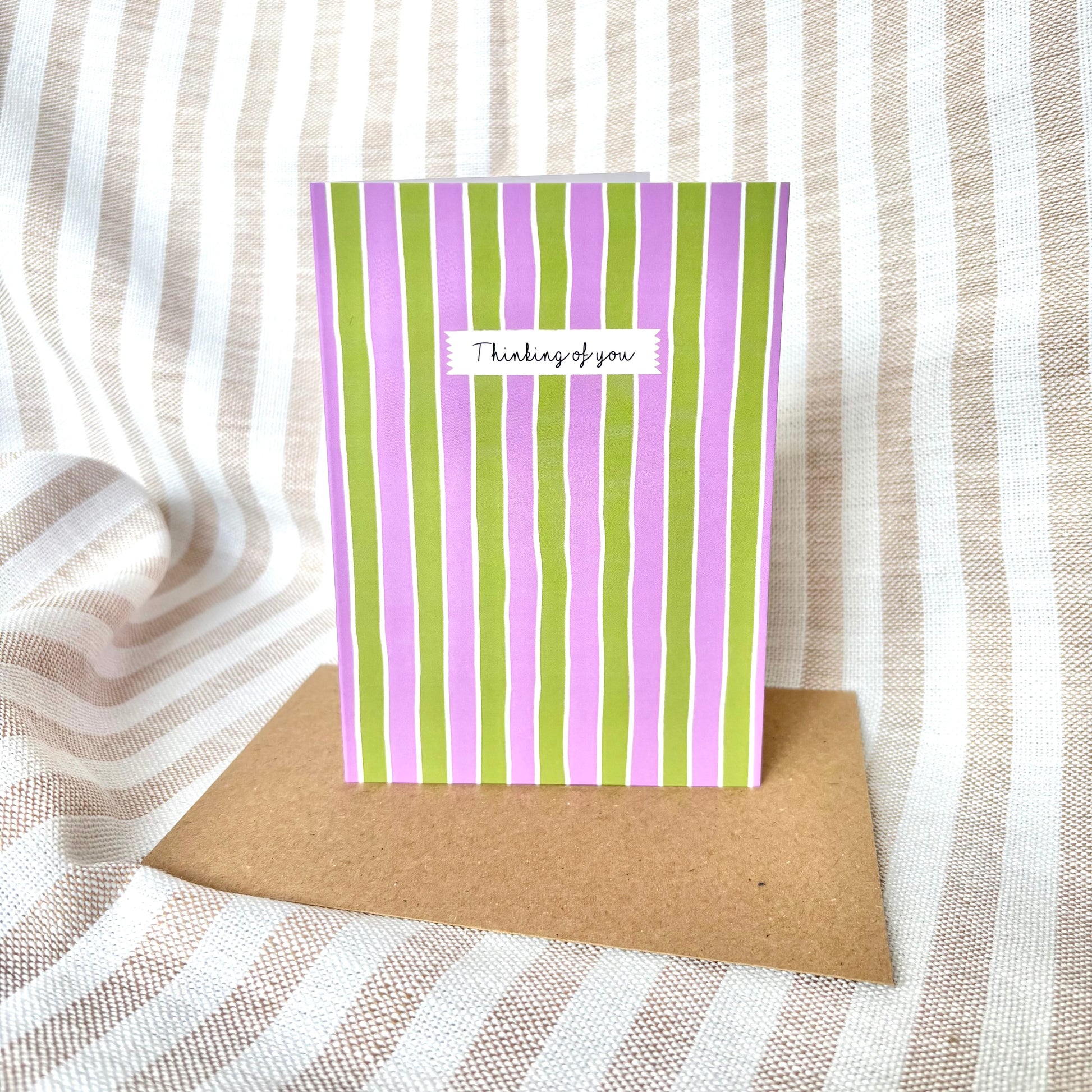 Striped card with 'Thinking of you' message on a textured fabric background