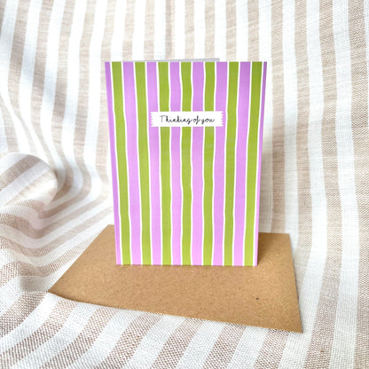 Striped card with 'Thinking of you' message on a textured fabric background