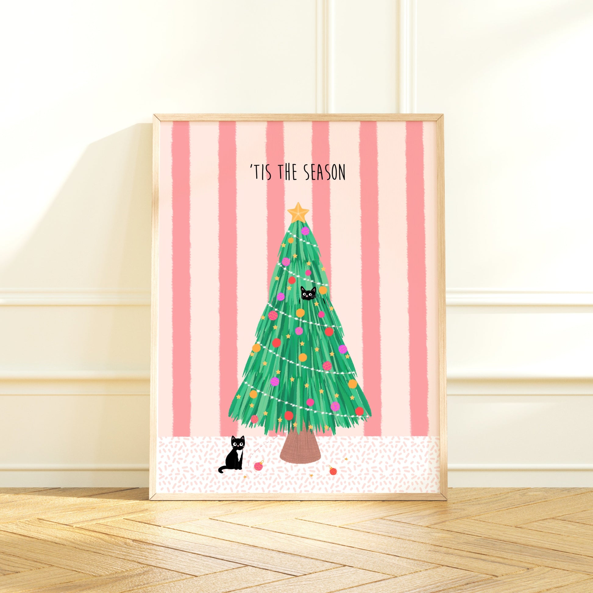 Framed artwork with a Christmas tree, 2 black cats and 'Tis the Season text on a pink striped background.