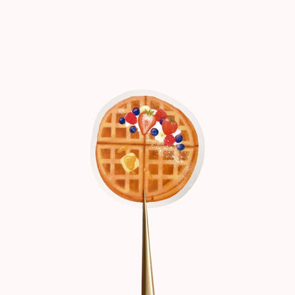 A transparent sticker with a detailed illustration of some breakfast waffles with syrup, butter and mixed summer berries