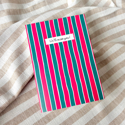 Striped card with 'We'll miss you!' message on a striped fabric background