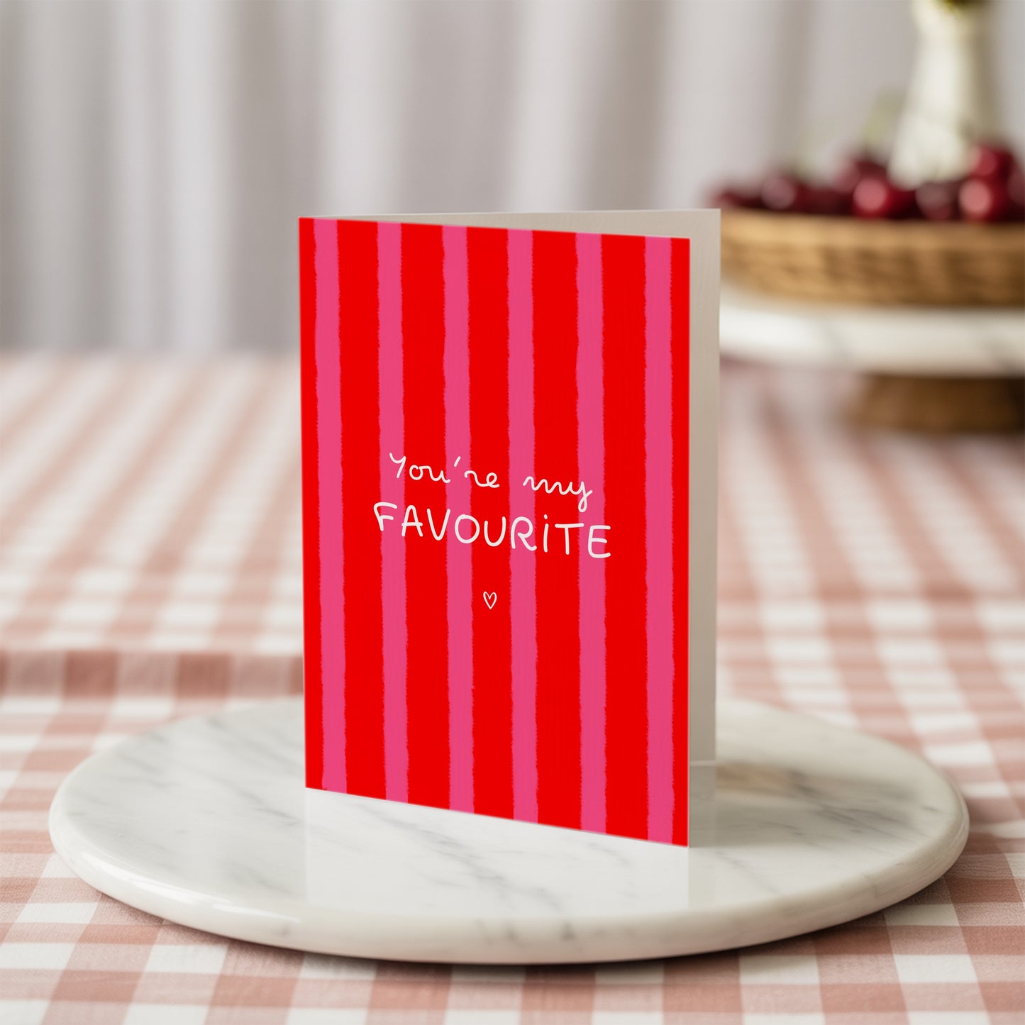 Red striped card with 'You're my Favourite' text on a marble coaster with a checkered tablecloth background