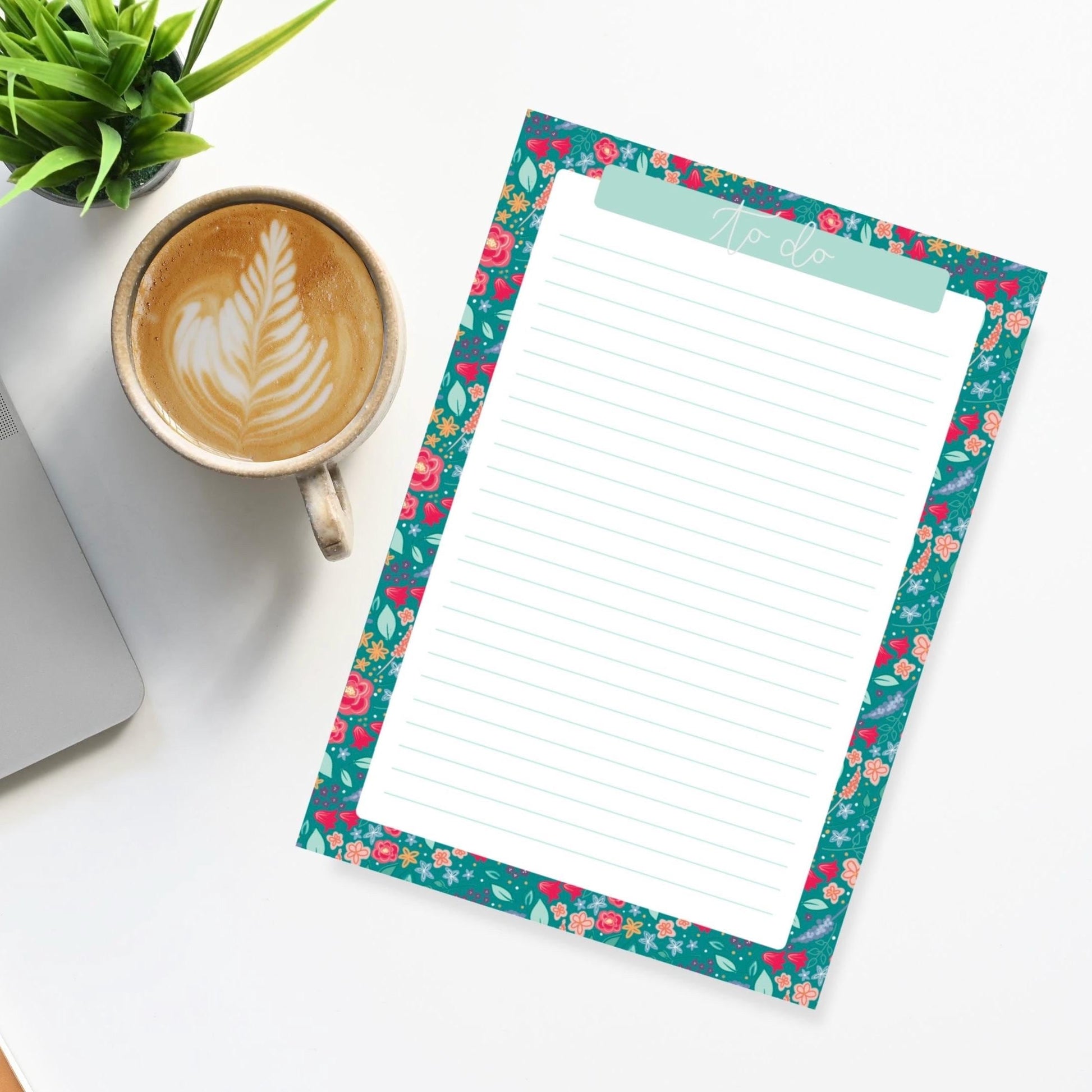 Floral border notepad with a cup of coffee and laptop on a white surface