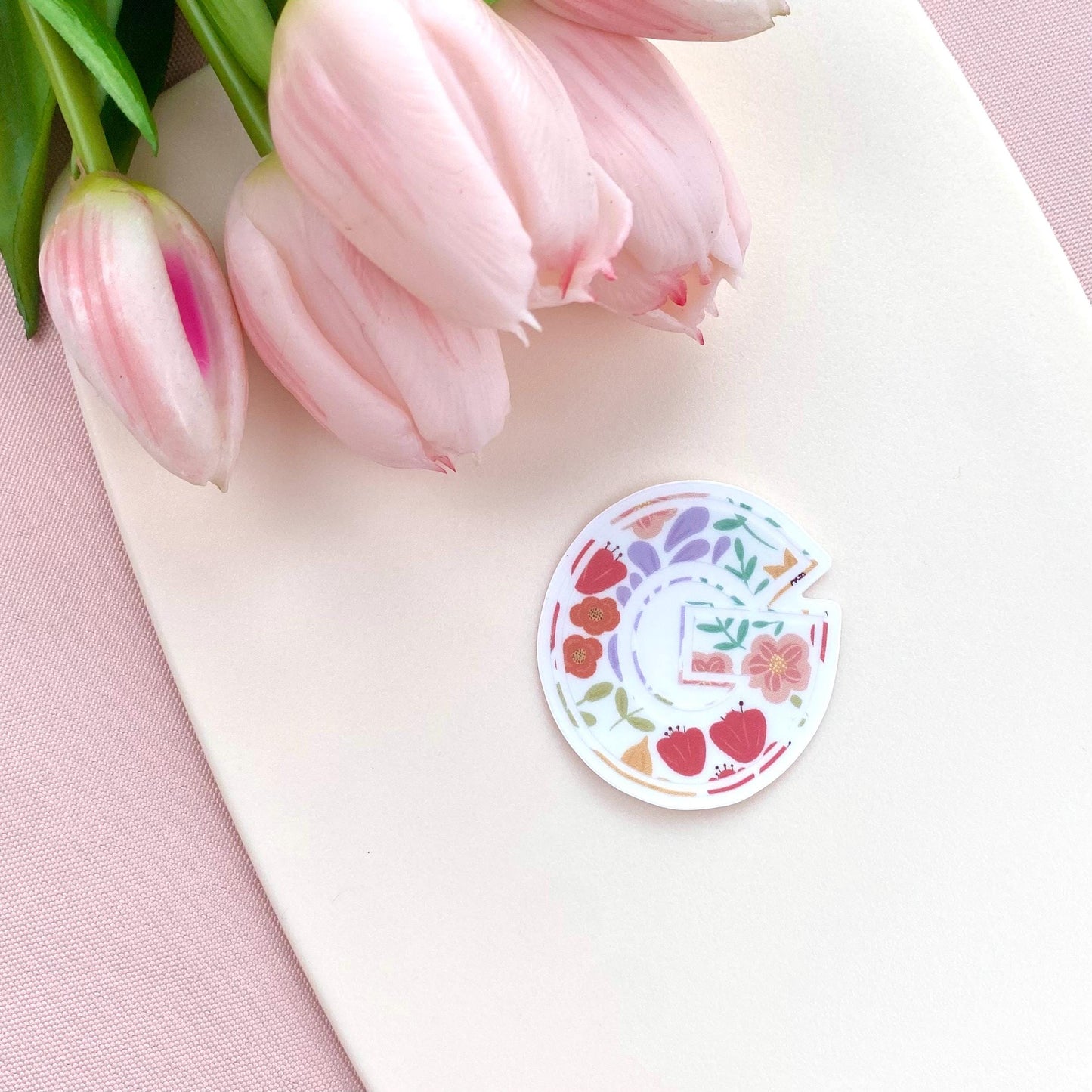 Decorative letter 'G' sticker with floral design on a white background with pink tulips