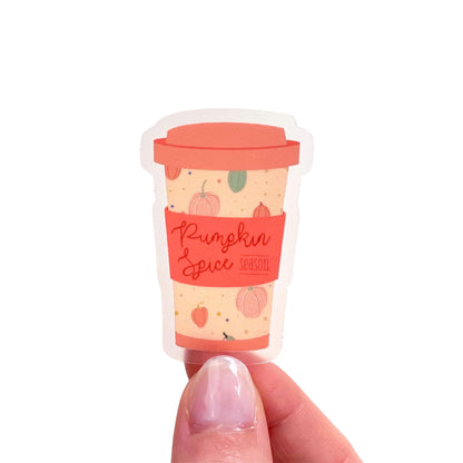 Miniature pumpkin spice latte sticker with a hand holding it against a white background