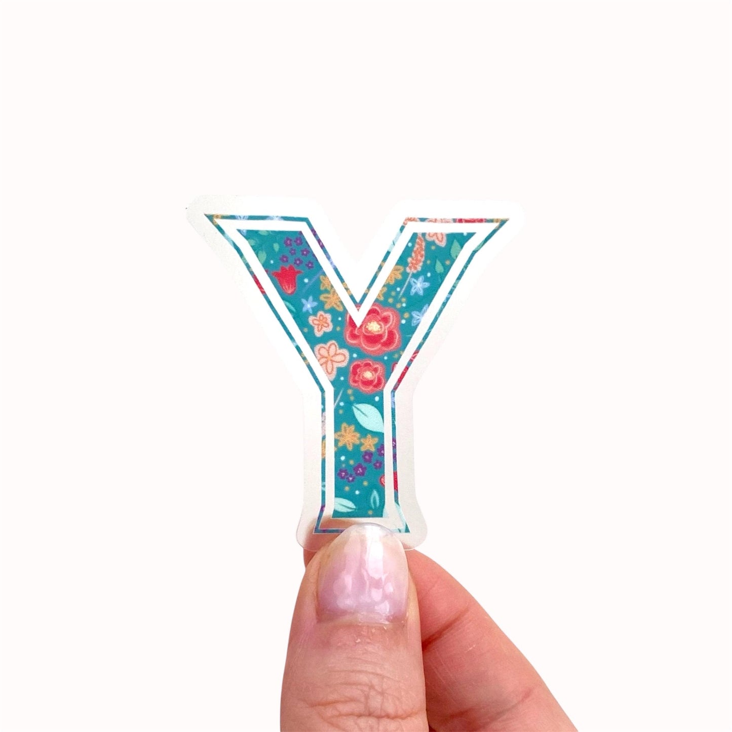 Decorative letter 'Y' sticker with floral pattern held by a hand on a white background