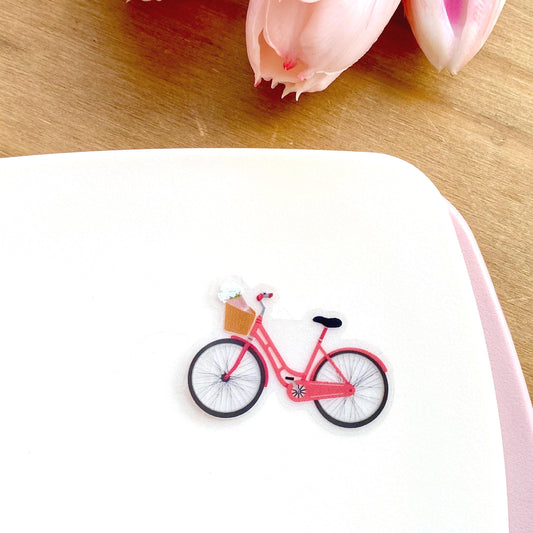 Pink bicycle sticker against a cream background.