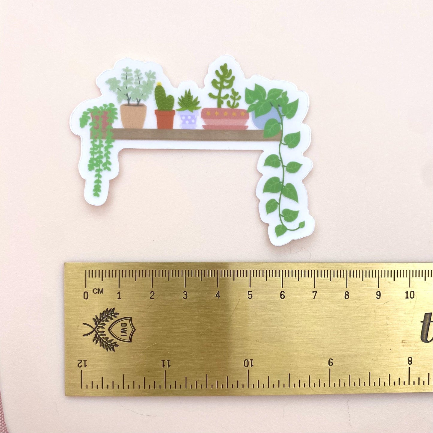 Sticker of a plant shelf with a ruler for scale on a light pink background