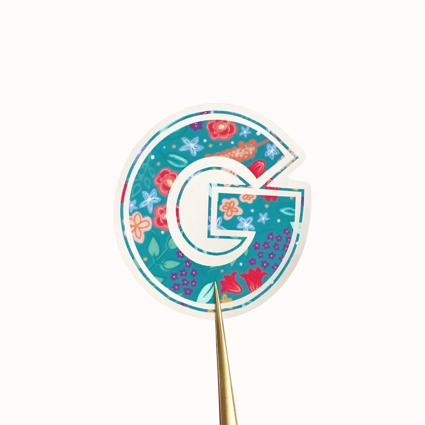 Decorative letter 'G' sticker with floral pattern on a white background