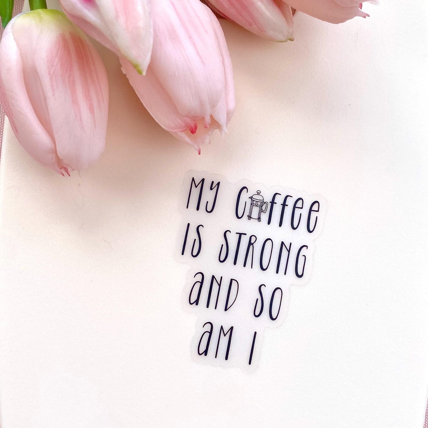 A transparent sticker with 'My coffee is strong and so am I' text against a white background