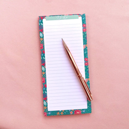 Floral notepad with a pen on a pink background