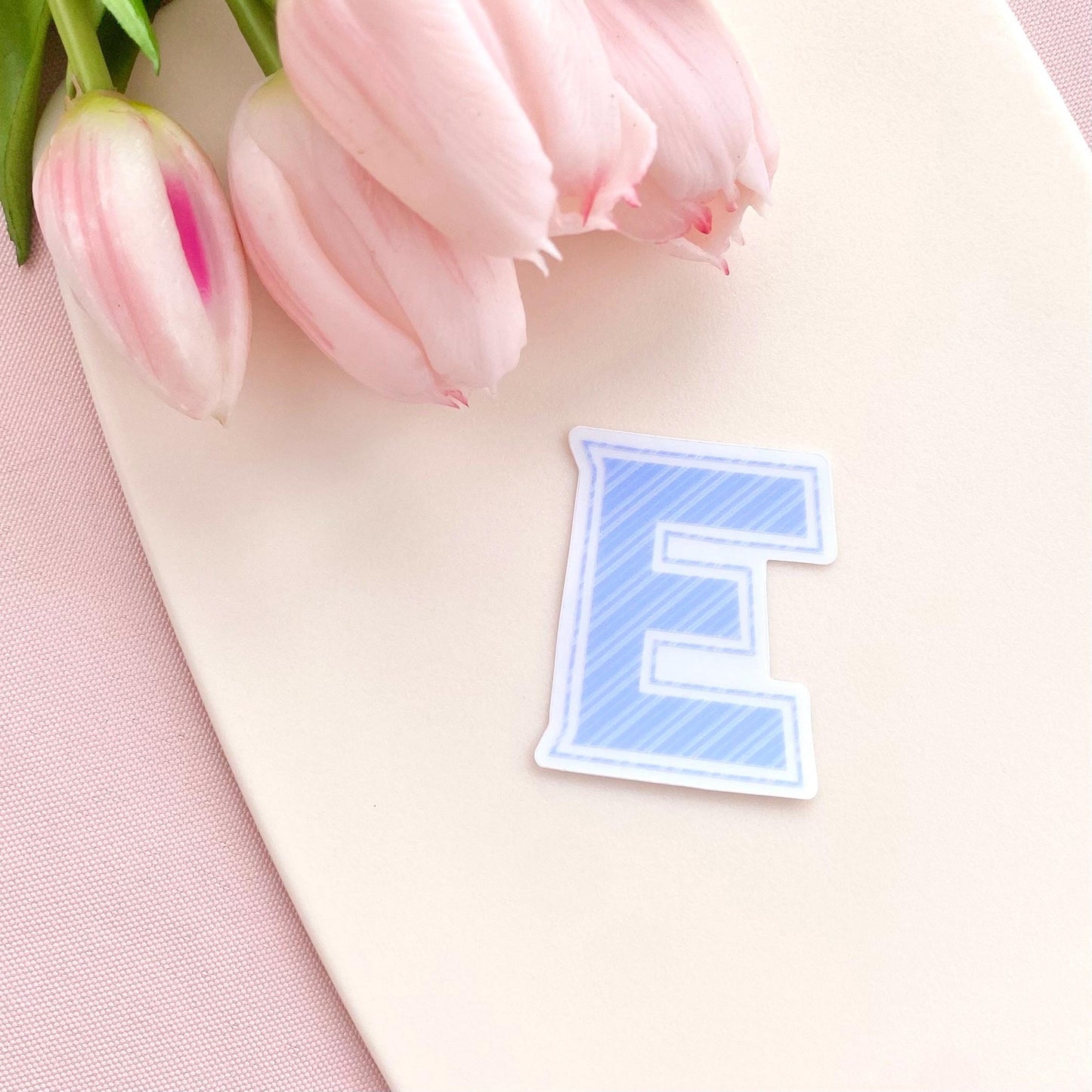 Blue striped letter 'S' transparent sticker on a white background with pink tulips