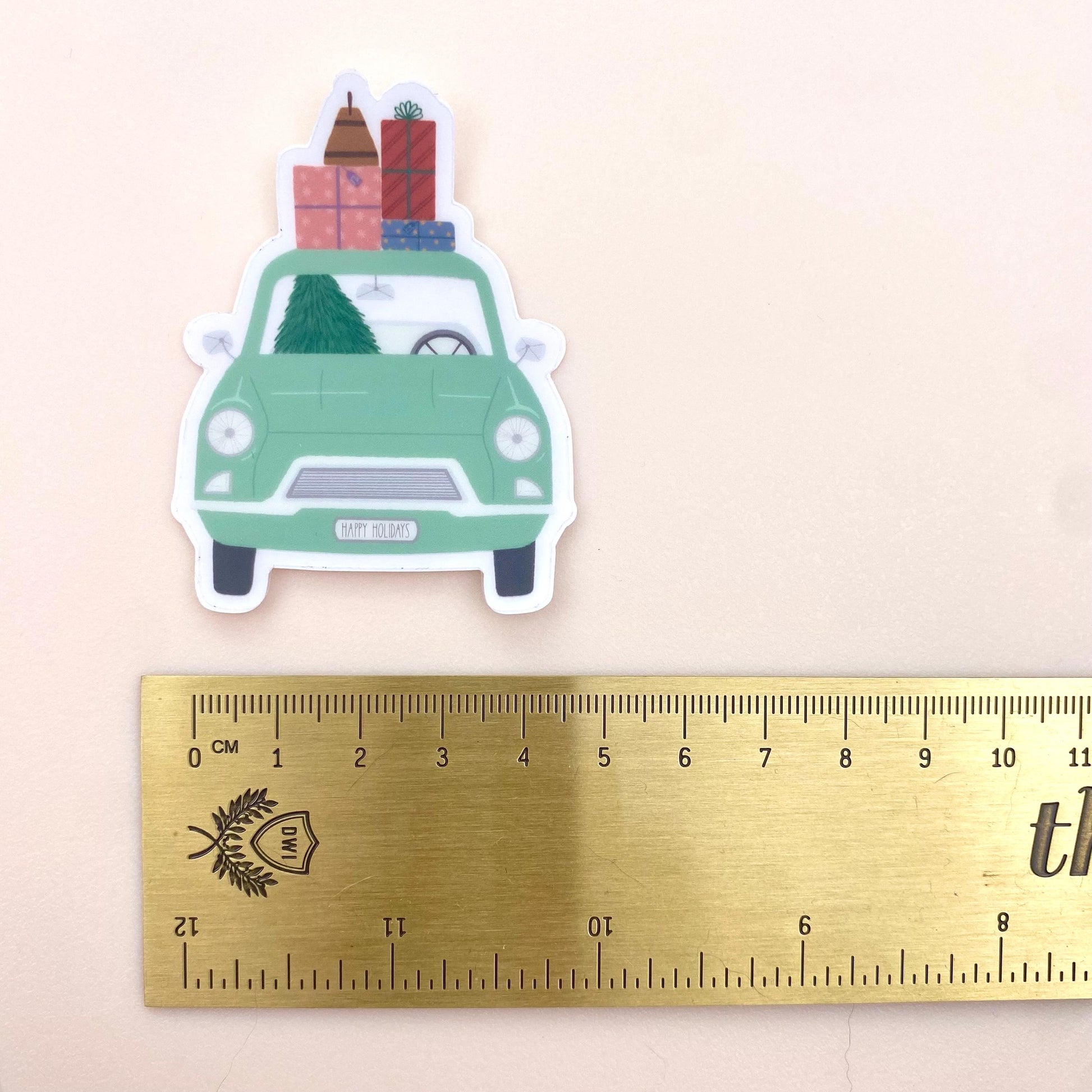Sticker of a green car with Christmas decorations next to a ruler for scale