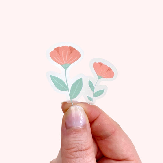 Hand holding a clear sticker with two pink flowers design on a white background.