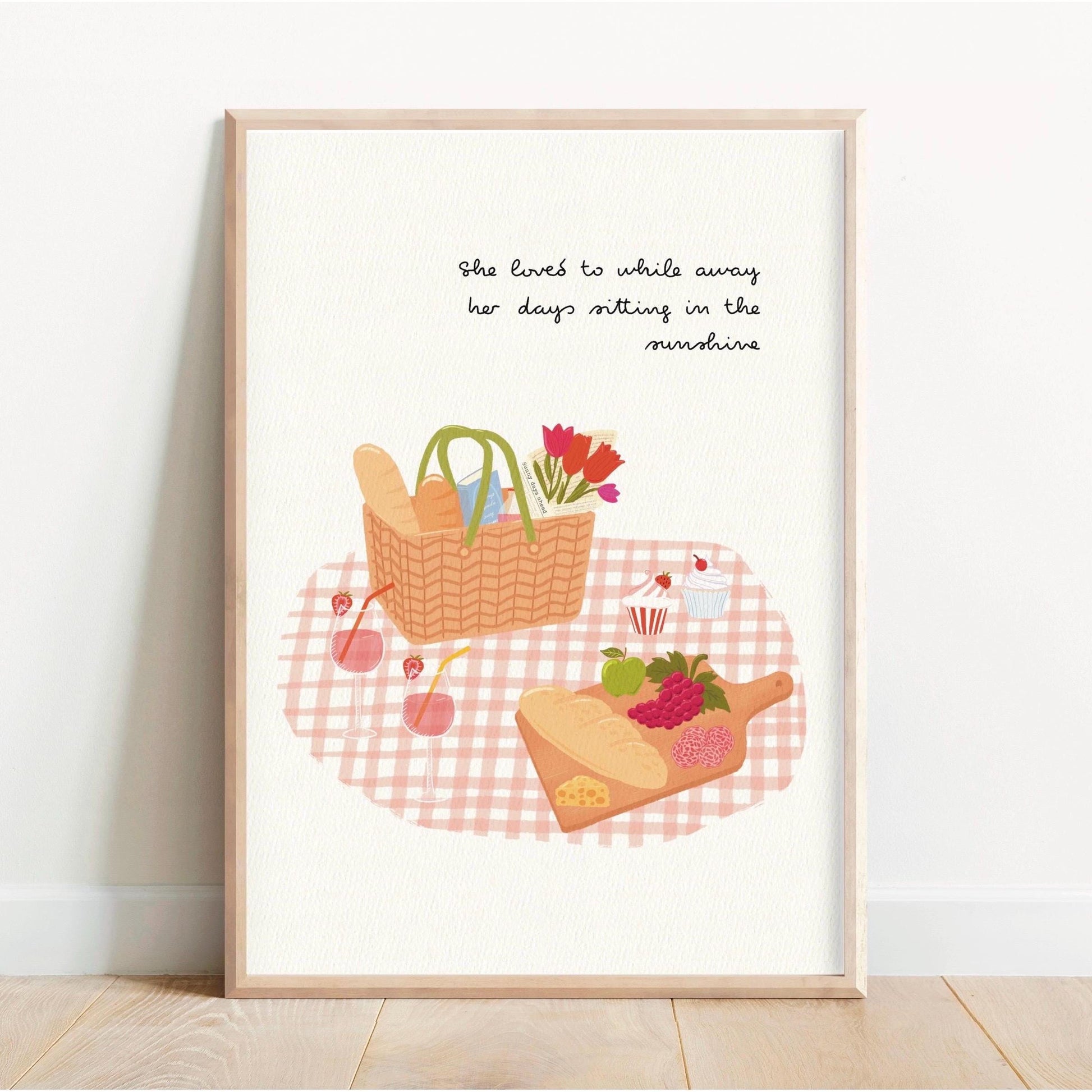 Framed artwork of a picnic scene with a basket, bread, and flowers on a checkered tablecloth.