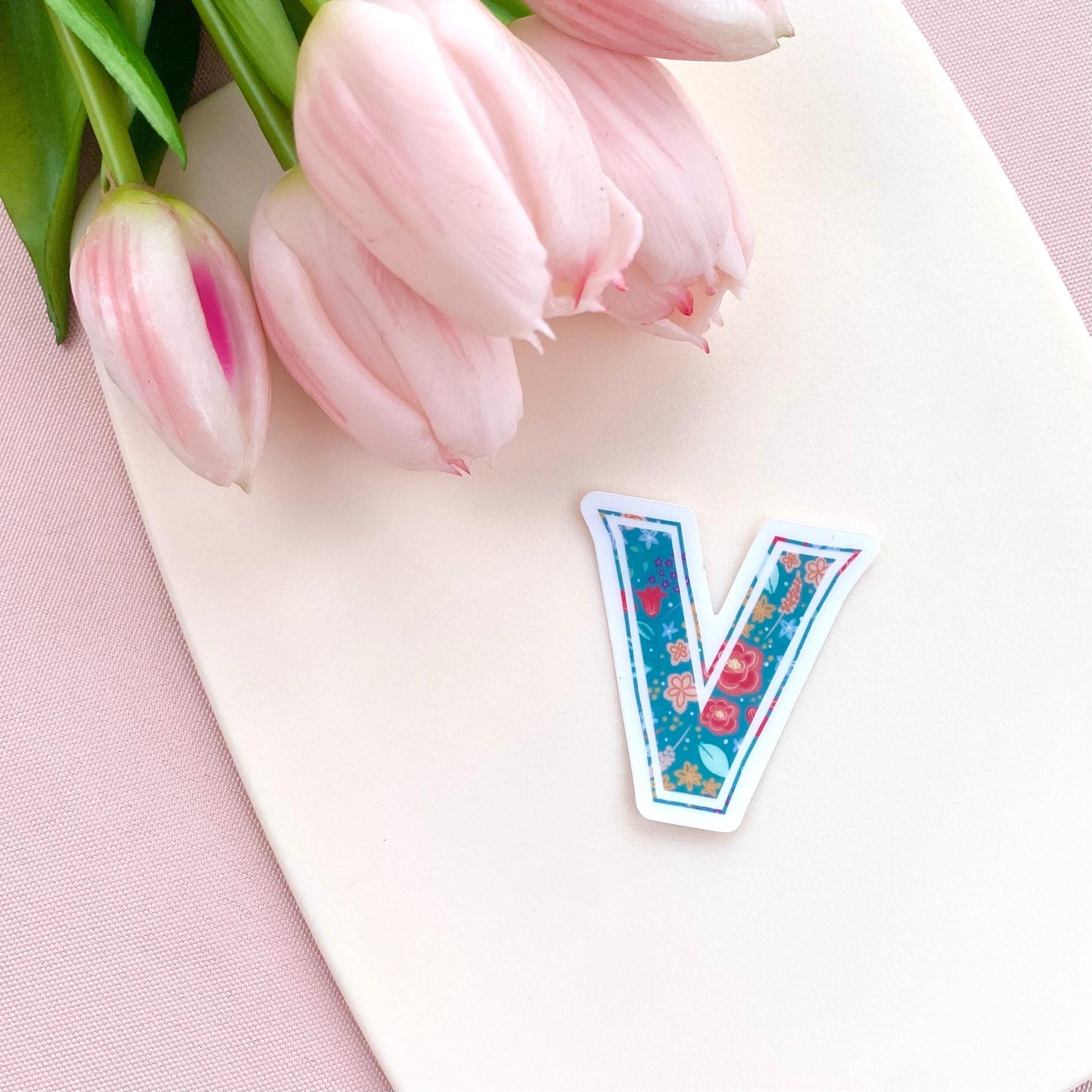Decorative letter 'V' sticker with floral design on a white background with pink tulips