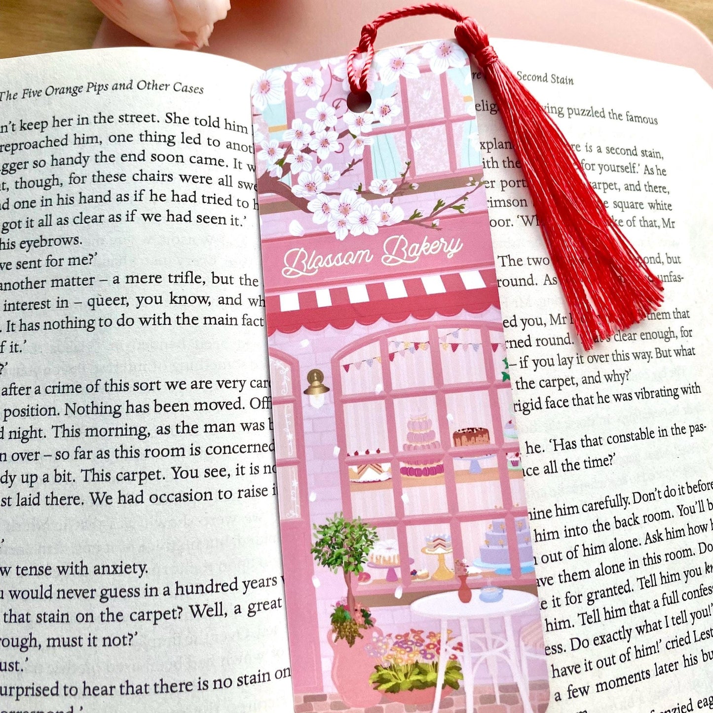 Bookmark with tassel on an open book, featuring 'Blossom Bakery' design.