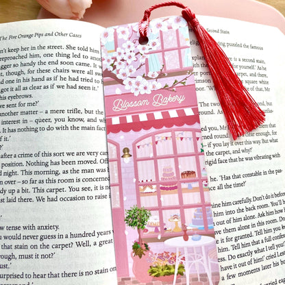 Bookmark with tassel on an open book, featuring 'Blossom Bakery' design.