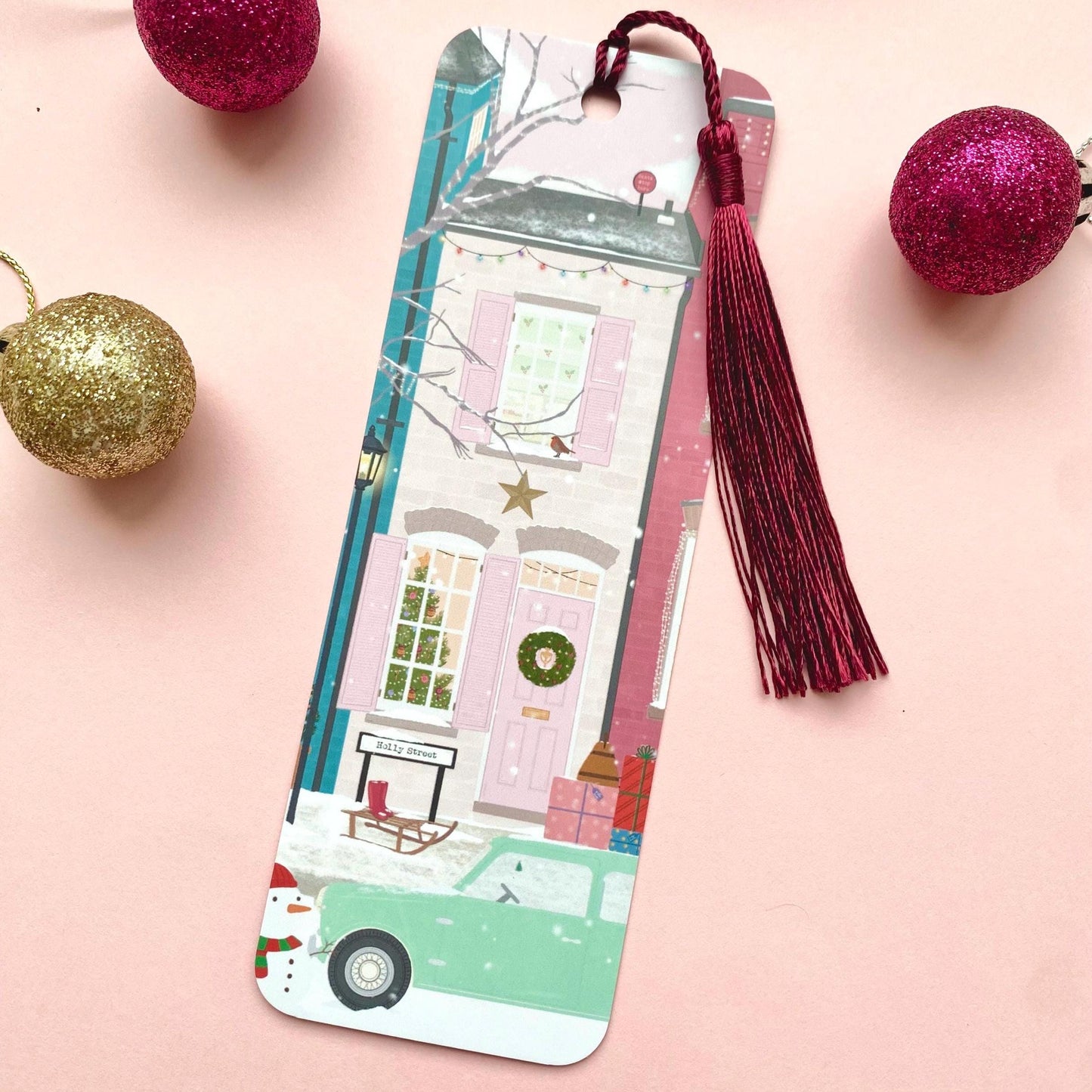 Decorative bookmark with tassel on a pink background with Christmas ornaments