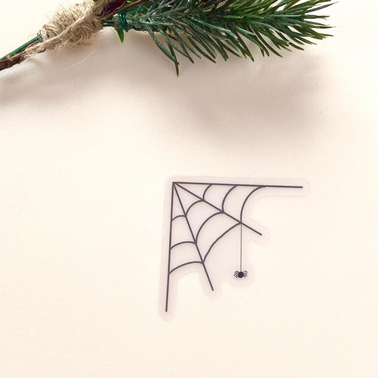 Transparent sticker with corner spider web design with a hanging spider on a white background