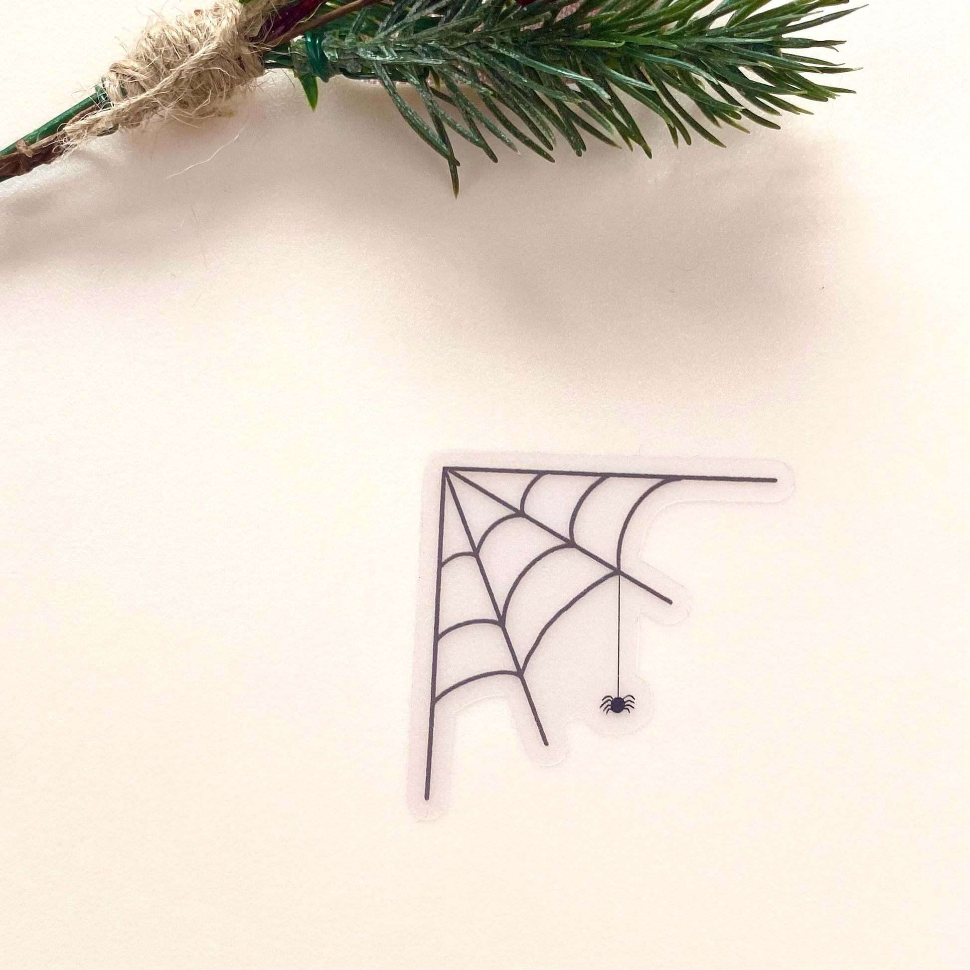 Transparent sticker with corner spider web design with a hanging spider on a white background