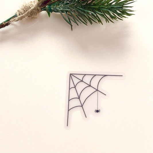 Transparent sticker with corner spider web design with a hanging spider on a white background