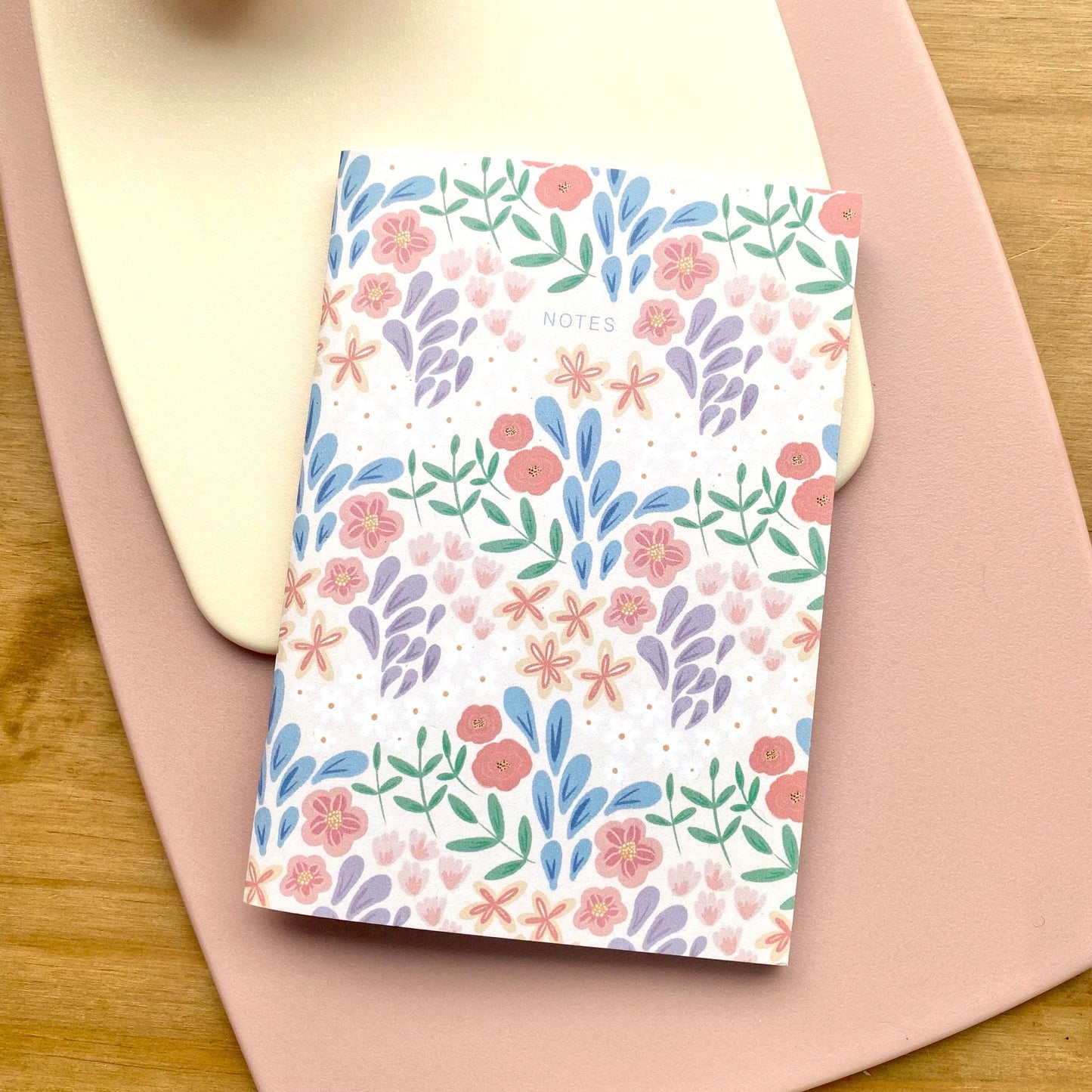 Notebook with floral pattern on a pink surface