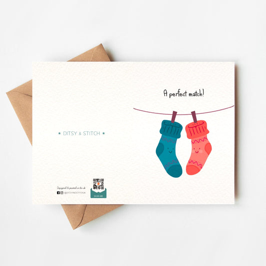 Greeting card with two socks on a line and 'A perfect match!' text, featuring Ditsy & Stitch branding on the back.