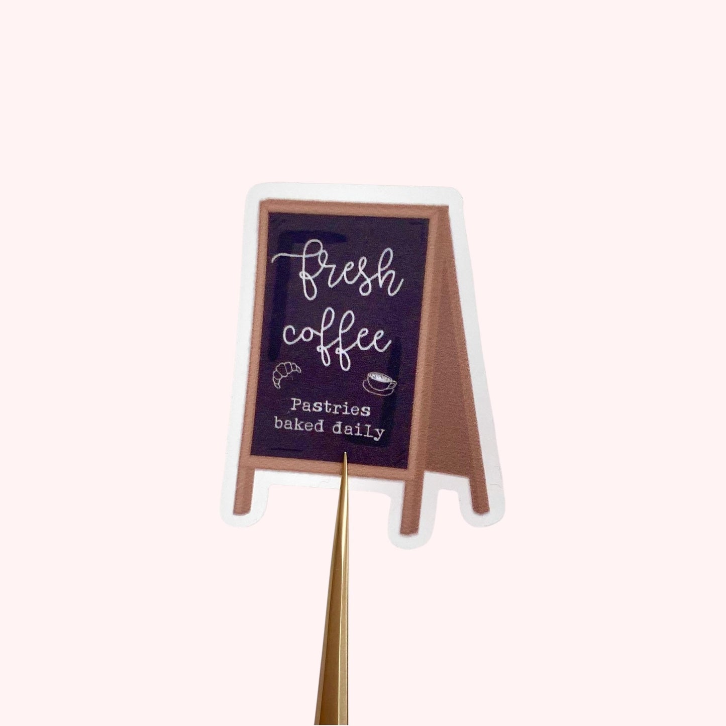 Sticker of an A-frame blackboard sign with 'Fresh coffee' and 'Pastries baked daily' text on a white background