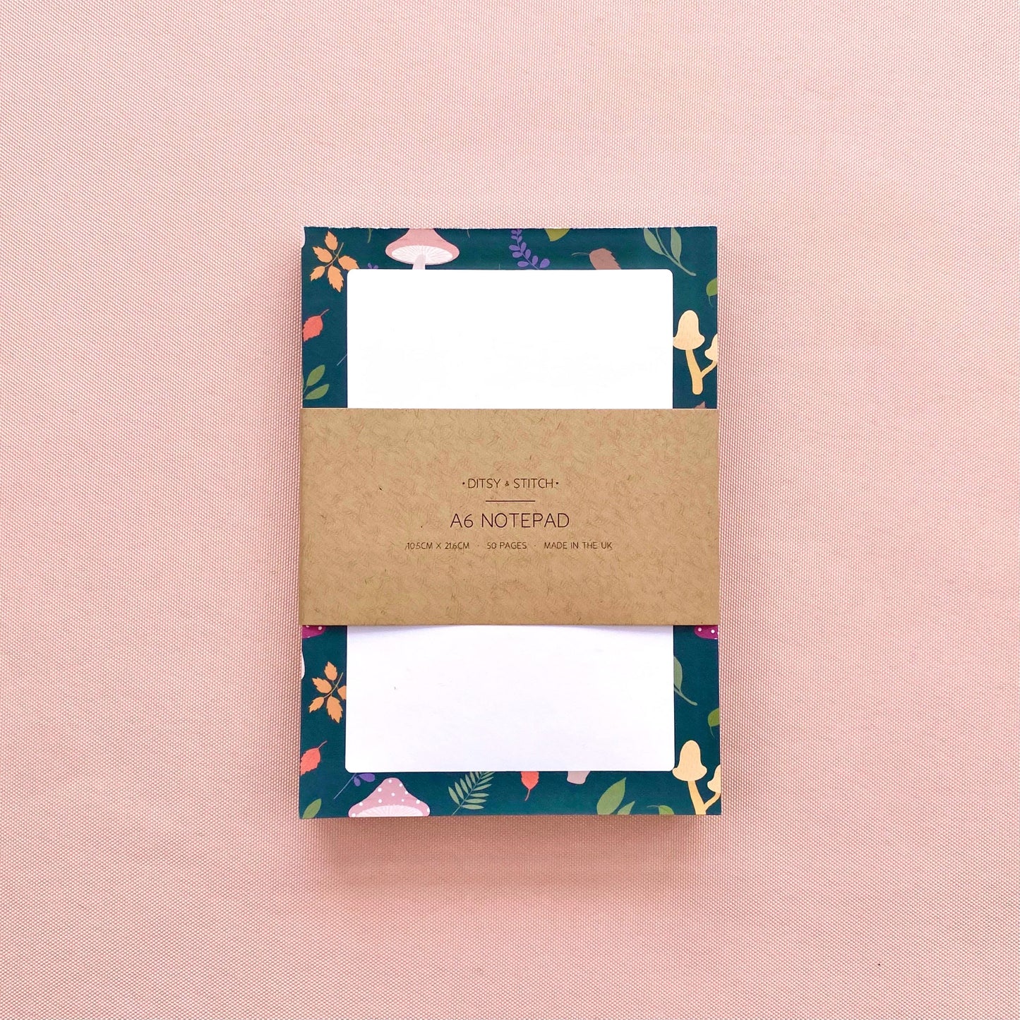Notepad with mushroom and leaf patterned border on a pink background