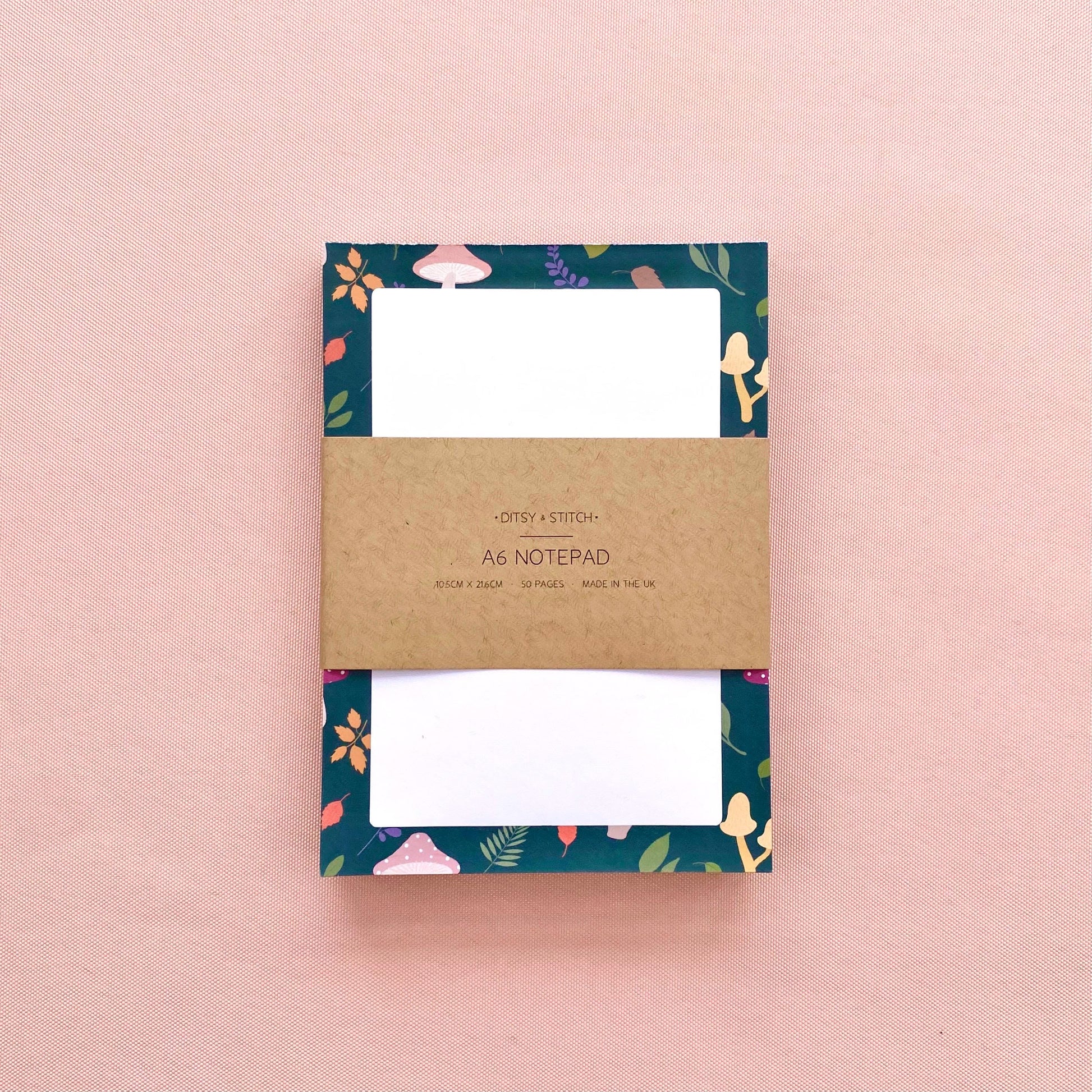 Notepad with mushroom and leaf patterned border on a pink background
