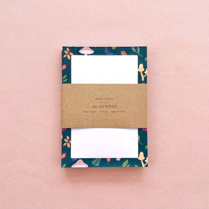 Notepad with mushroom and leaf patterned border on a pink background