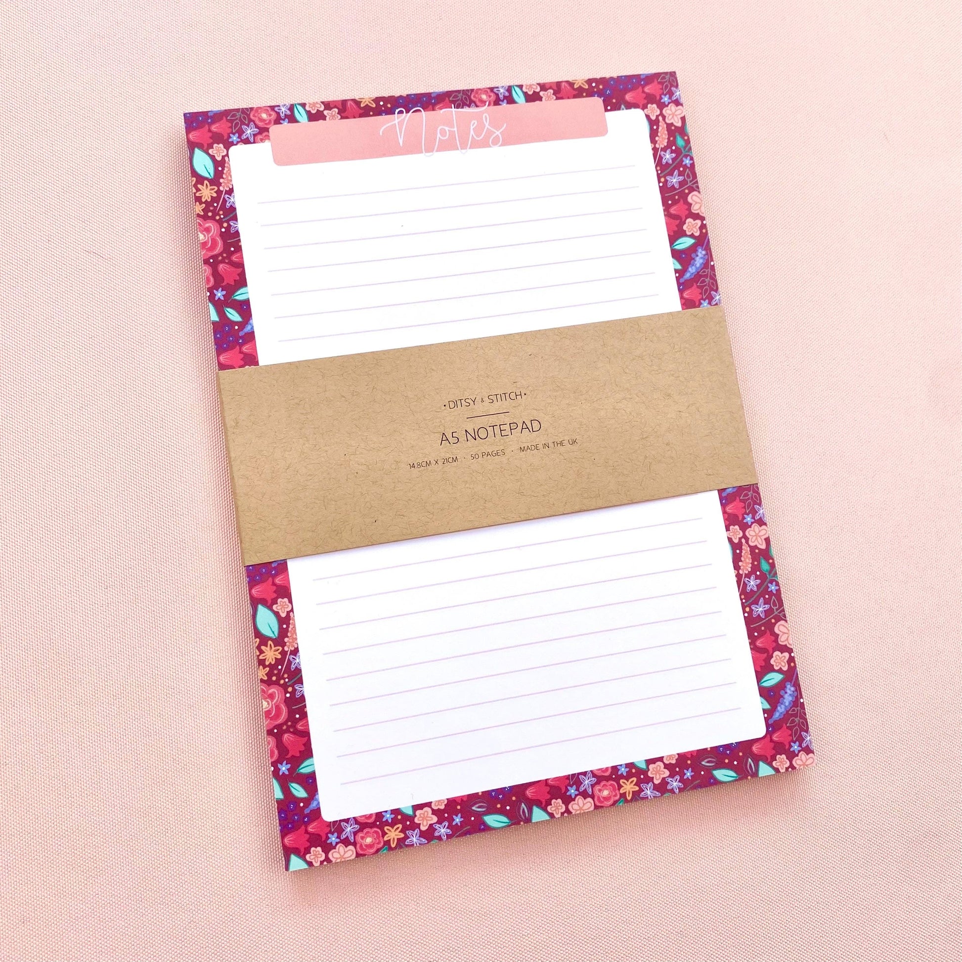 Floral notepad with a brown kraft paper label on a pink background