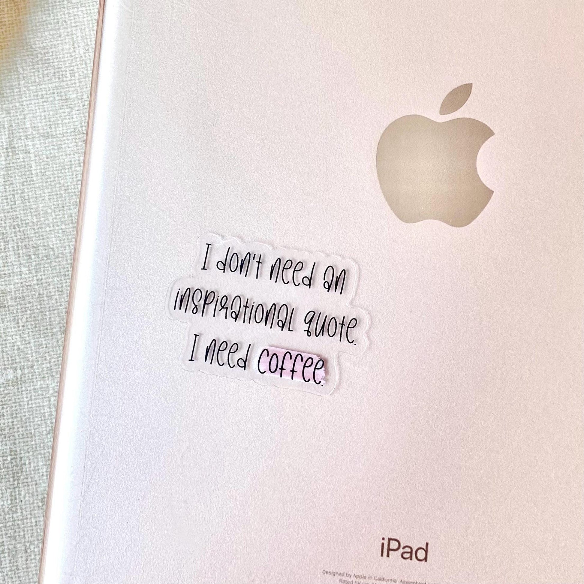 Clear vinyl sticker with black text 'I don't need an inspirational quote, I need coffee' shown on the back of an ipad