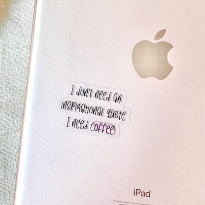 Clear vinyl sticker with black text 'I don't need an inspirational quote, I need coffee' shown on the back of an ipad