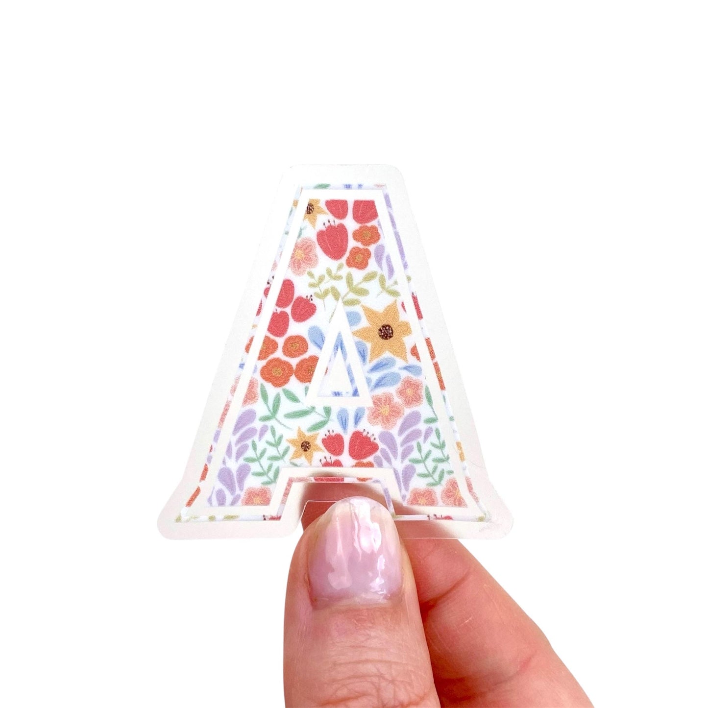 Decorative letter 'A' sticker with floral pattern held by hand against a white background