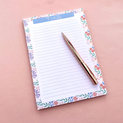 Floral notepad with a pen on a pink background