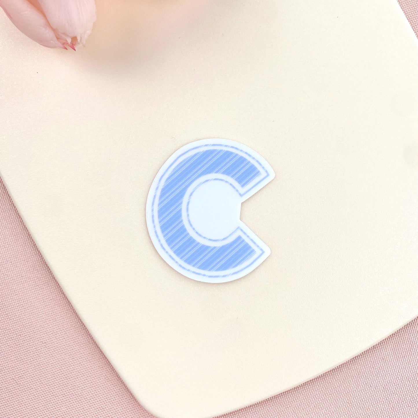 Blue letter 'c' sticker on a light pink background