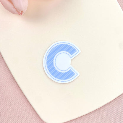 Blue letter 'c' sticker on a light pink background