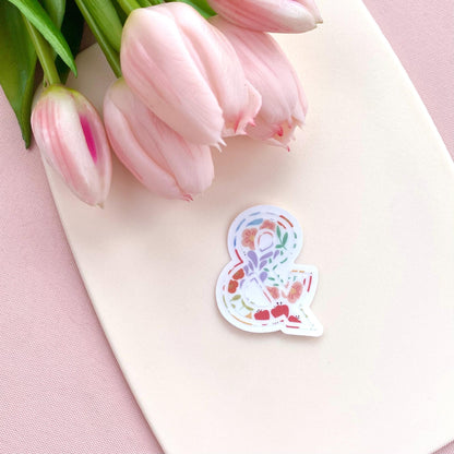 Floral sticker with an ampersand on a pink surface with tulips