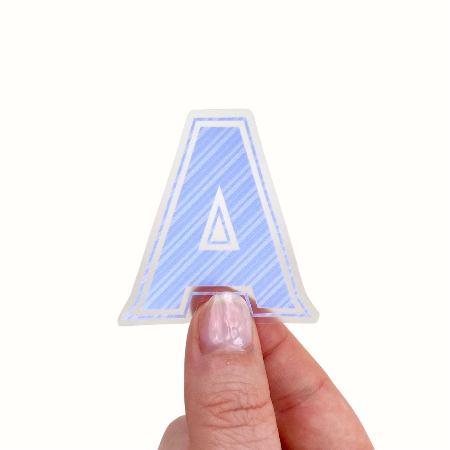 Hand holding a blue striped letter 'A' sticker against a white background